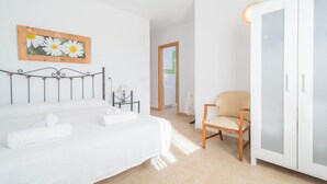 A bedroom with a bed, a chair, a wardrobe, and a painting on the wall.