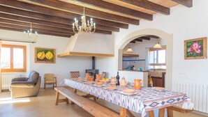 A dining area with a long table set for a meal, wooden benches, and a chandelier.