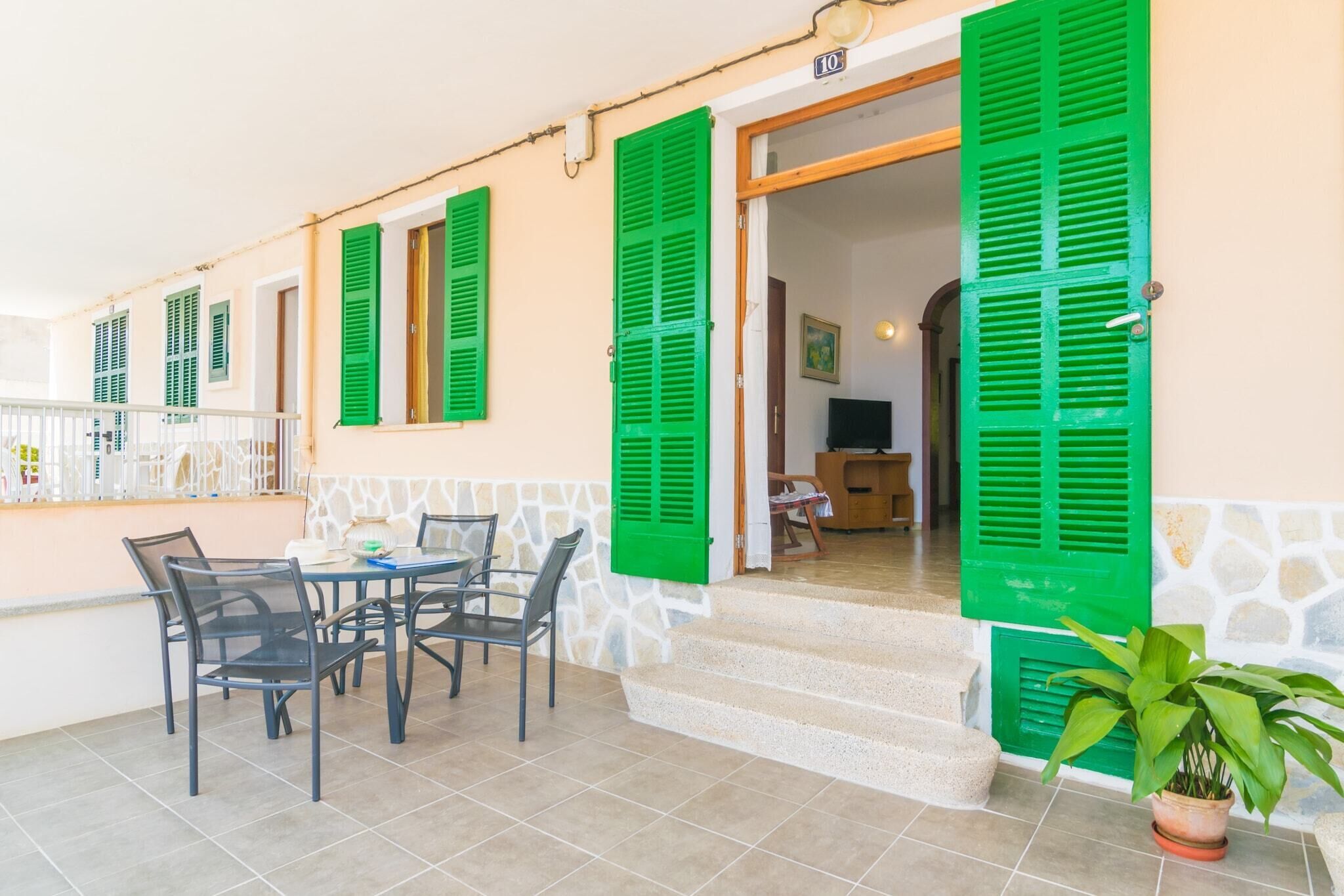 Eine Terrasse mit Sitzgelegenheiten im Freien, grünen Fensterläden und einem Blumentopf.