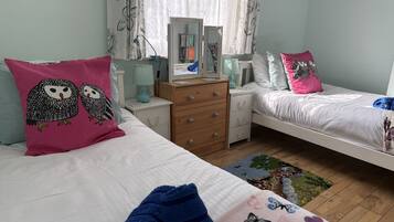 Un dormitorio con dos camas, un aparador, un espejo y una ventana con cortinas.