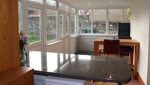 Una cocina moderna con ventanas amplias, encimera de granito y zona de comedor con mobiliario de madera.