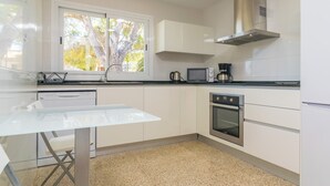 Een moderne keuken met witte kastjes, een roestvrijstalen oven, een magnetron en een koffiezetapparaat.