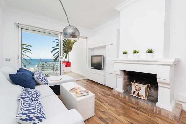 Een moderne woonkamer met een witte bank, een open haard en uitzicht op zee.