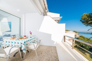 Een balkon met een ontbijtinstelling, met uitzicht op de kust.