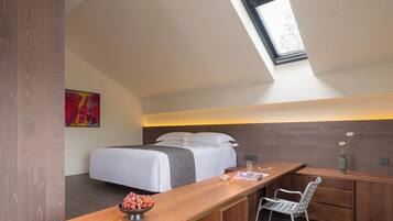 A modern bedroom with a skylight, a bed, a desk, and a chair.