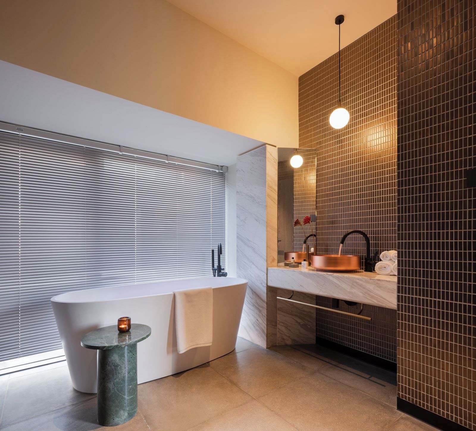 Une salle de bain moderne avec une baignoire sur pieds, un meuble-lavabo avec un vasque en cuivre et un grand miroir.