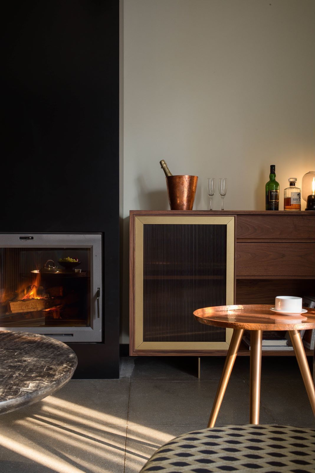 A modern living room with a fireplace, a wooden cabinet, and a round table.