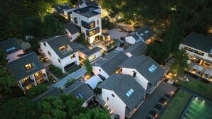 An aerial view of a residential area with modern houses, a swimming pool, and well-lit streets. - Tan Alley Wuzhen Eco and Cultural Community (Jiaxing)