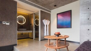 A modern spa room with a round wooden table, a large abstract painting, and a view of the bathroom. - Tan Alley Wuzhen Eco and Cultural Community (Jiaxing)