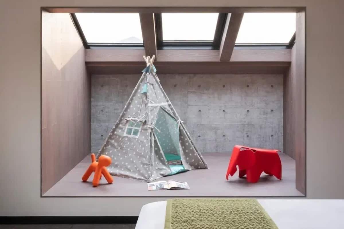 A room with a skylight, a tent, a red chair, and a small orange figure.