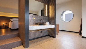 A modern bathroom with a dark tiled wall, a round mirror, and a white sink. - Tan Alley Wuzhen Eco and Cultural Community (Jiaxing)