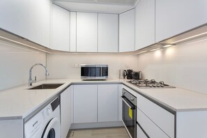 A modern kitchen with white cabinets, a built-in microwave, a gas stove, a sink, and a dishwasher.