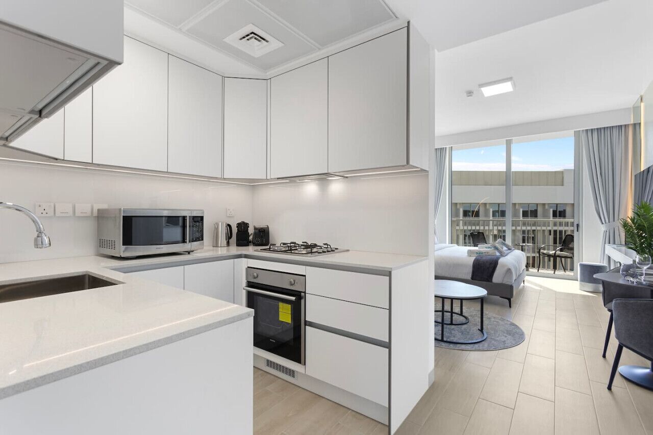 A modern kitchen with white cabinets, a microwave, and a gas stove.