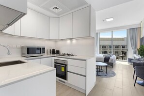 A modern kitchen with white cabinets, a microwave, and a gas stove. - Perfect Getaway modern Studio in Luma 22 - JVC (Dubai)