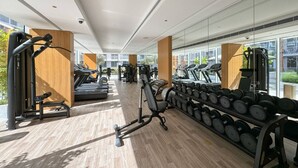 A modern gym with treadmills, weight machines, and dumbbells. - Perfect Getaway modern Studio in Luma 22 - JVC (Dubai)