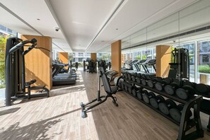 A modern gym with treadmills, weight machines, and dumbbells.