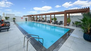 A rooftop pool with lounge chairs and a pergola. - Perfect Getaway modern Studio in Luma 22 - JVC (Dubai)