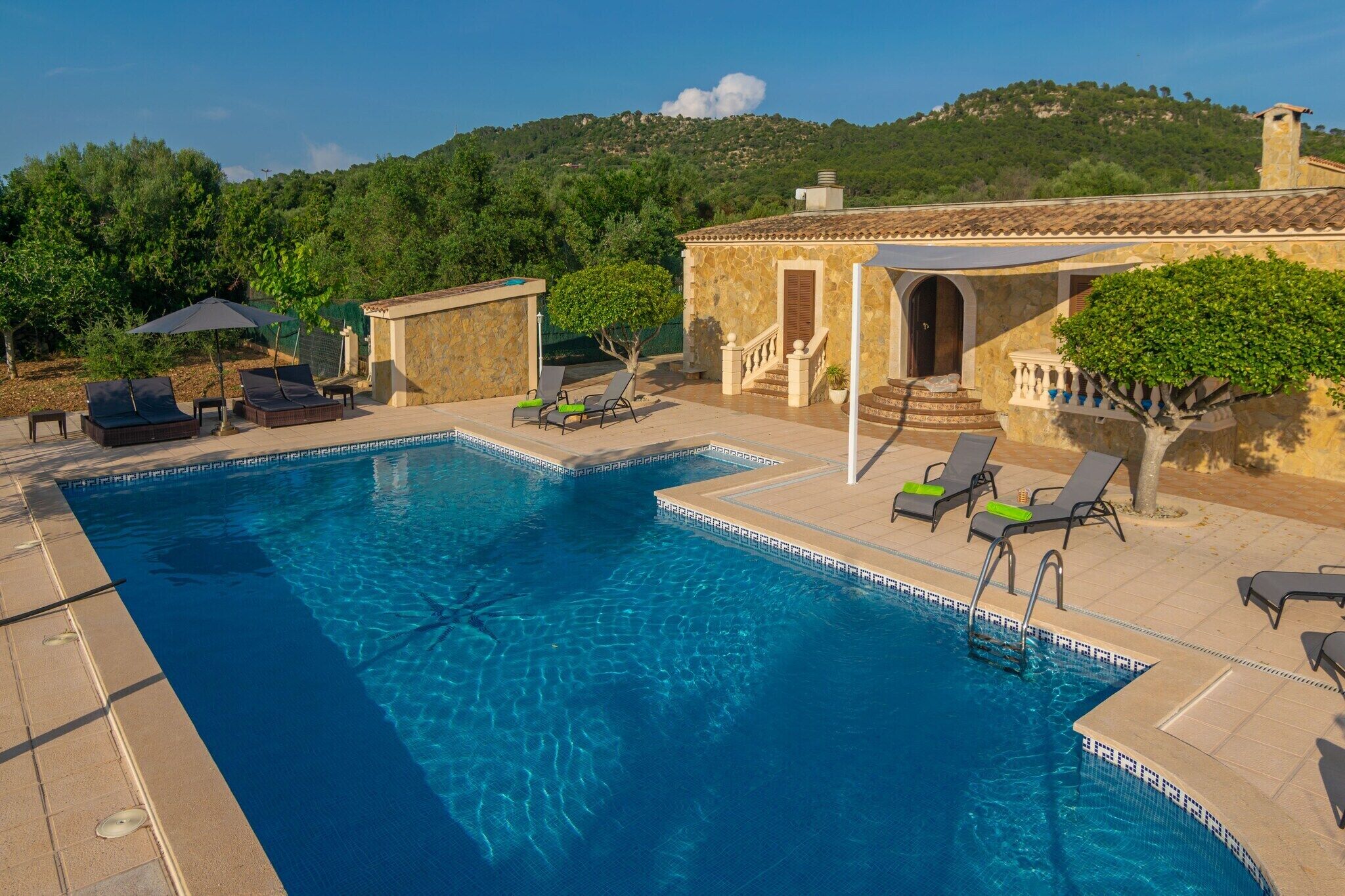 A swimming pool with lounge chairs and a stone building with a staircase.
