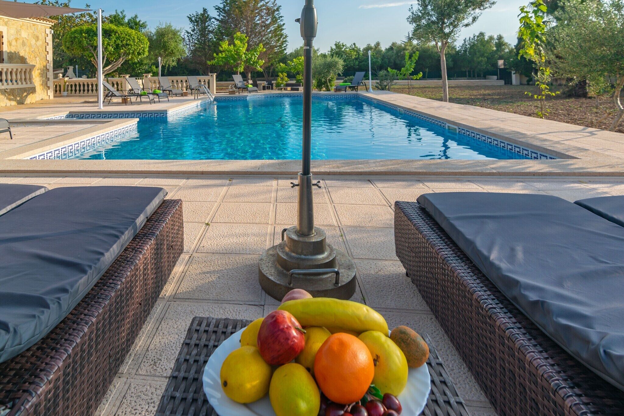 A swimming pool with lounge chairs and a fruit plate in the foreground.