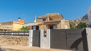 A modern house with a stone facade, a large wooden deck, and a gated entrance. - Can Clavell - Villa With Private Pool. Free Wifi (Colonia De Sant Pere (artà), Illes Balears)