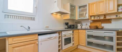 A kitchen with a dishwasher, oven, and a coffee maker.
