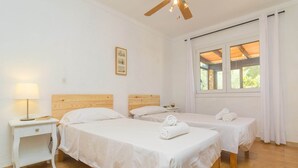 A hotel room with two single beds, a wooden headboard, a nightstand with a lamp, and a window with curtains. - Can Clavell - Villa With Private Pool. Free Wifi (Colonia De Sant Pere (artà), Illes Balears)
