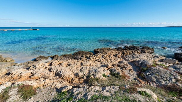 A rocky shoreline with clear blue water and a distant pier. - 3 C'an Boto - Villa With Private Pool In Manacor (Manacor, Illes Balears)