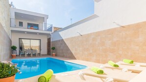 A modern outdoor pool area with lounge chairs and a dining table.