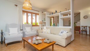 Ein Wohnzimmer mit einer Couch, zwei Sesseln, einem Holztisch und einer Pendelleuchte.