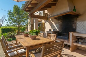 An outdoor patio with a wooden table and chairs, surrounded by potted plants. - Can Pilos - Apartment In Inca. Free Wifi (Inca, Illes Balears)