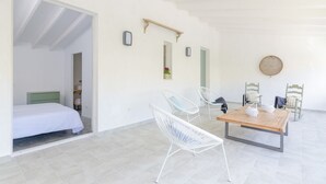 A room with a bed, a table with chairs, and a wall-mounted shelf. - Na Valenta - Villa With Private Pool In Artà (Artà, Illes Balears)