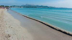 A beach with clear turquoise water, a sandy shore, and a distant mountain range. - Bellavista - Apartment In Port D'alcúdia (Port D'alcudia, Illes Balears)