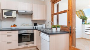 A modern kitchen with a microwave, oven, dishwasher, and a wooden door. - Bellavista - Apartment In Port D'alcúdia (Port D'alcudia, Illes Balears)