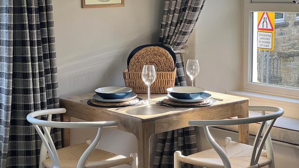 A dining table with two blue plates, two wine glasses, and a woven basket.