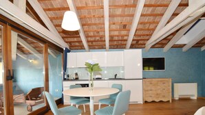 A modern kitchen with white cabinets, a round dining table, and light blue chairs. - Georgeous and Warm Living Downtown Rovinj (Rovinj)