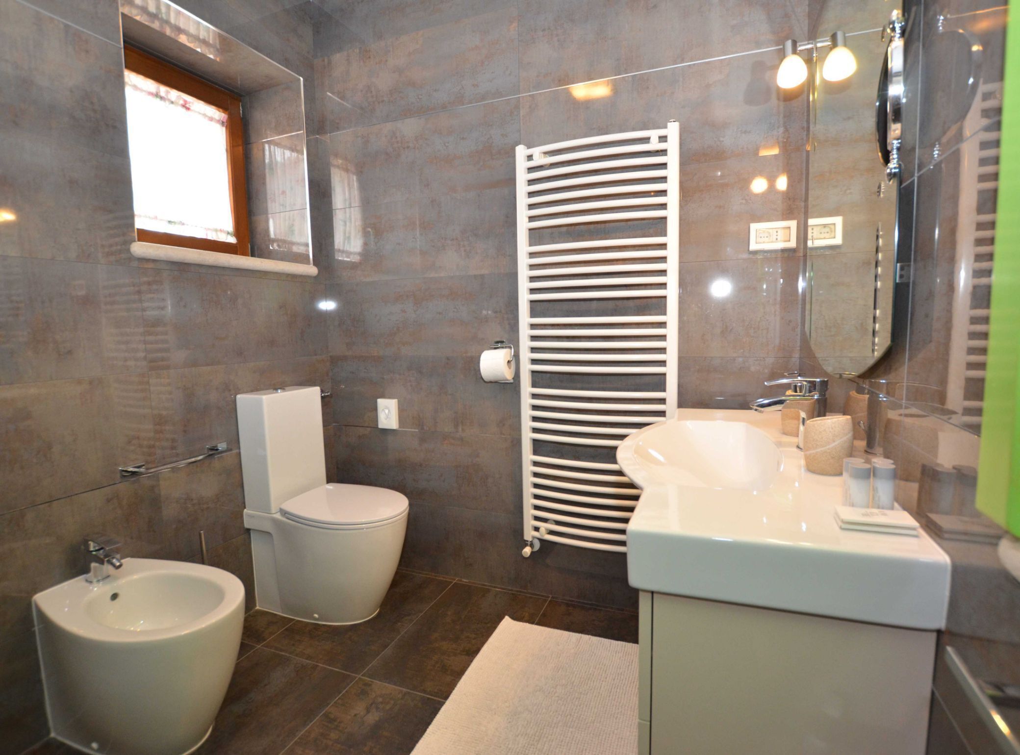 Un baño moderno con un bidé, inodoro y un espejo grande.