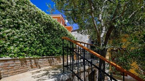A stone staircase with a metal railing, leading up to a building with a brick wall and a green hedge. - Georgeous and Warm Living Downtown Rovinj (Rovinj)