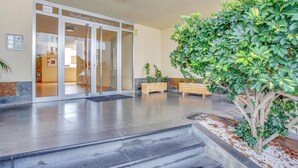 A modern hotel lobby with a glass entrance, a reception desk, and a staircase leading to the upper floors. - El Sol del Sur, Ocean View, 2 Pool, Fiber (Costa Adeje)