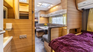 A compact RV interior with a bed, kitchenette, and seating area. - Caravan 'Max 2 Erw Und 2 Kd' with Shared Garden and Wi-Fi (Zeschdorf)