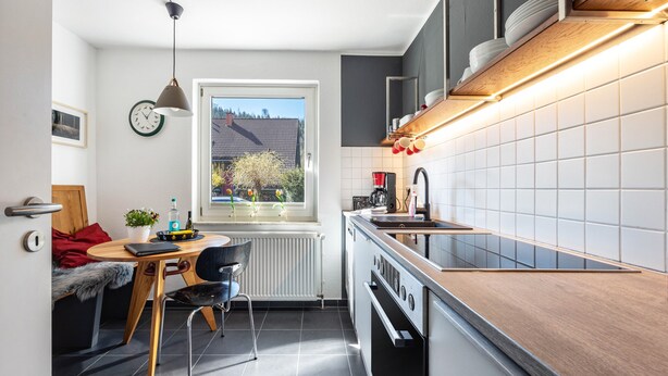 Moderni keittiö, jossa on ruokailutila, ikkunasta avautuva kaunis näkymä ja sisäänrakennettu uuni.