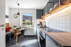 A modern kitchen with a dining area, a window with a view, and a built-in oven. - Holiday Home 'Waldgästehaus' with Wi-Fi (Horn-Bad Meinberg)