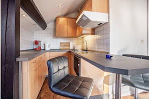 A modern kitchen with wooden cabinets, a built-in bench, a sink, and a coffee maker.