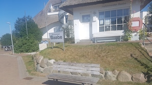 Un bâtiment sur lequel on peut lire l’inscription « Hafenmeister Baabe », un banc et une petite colline couverte d’herbe.
