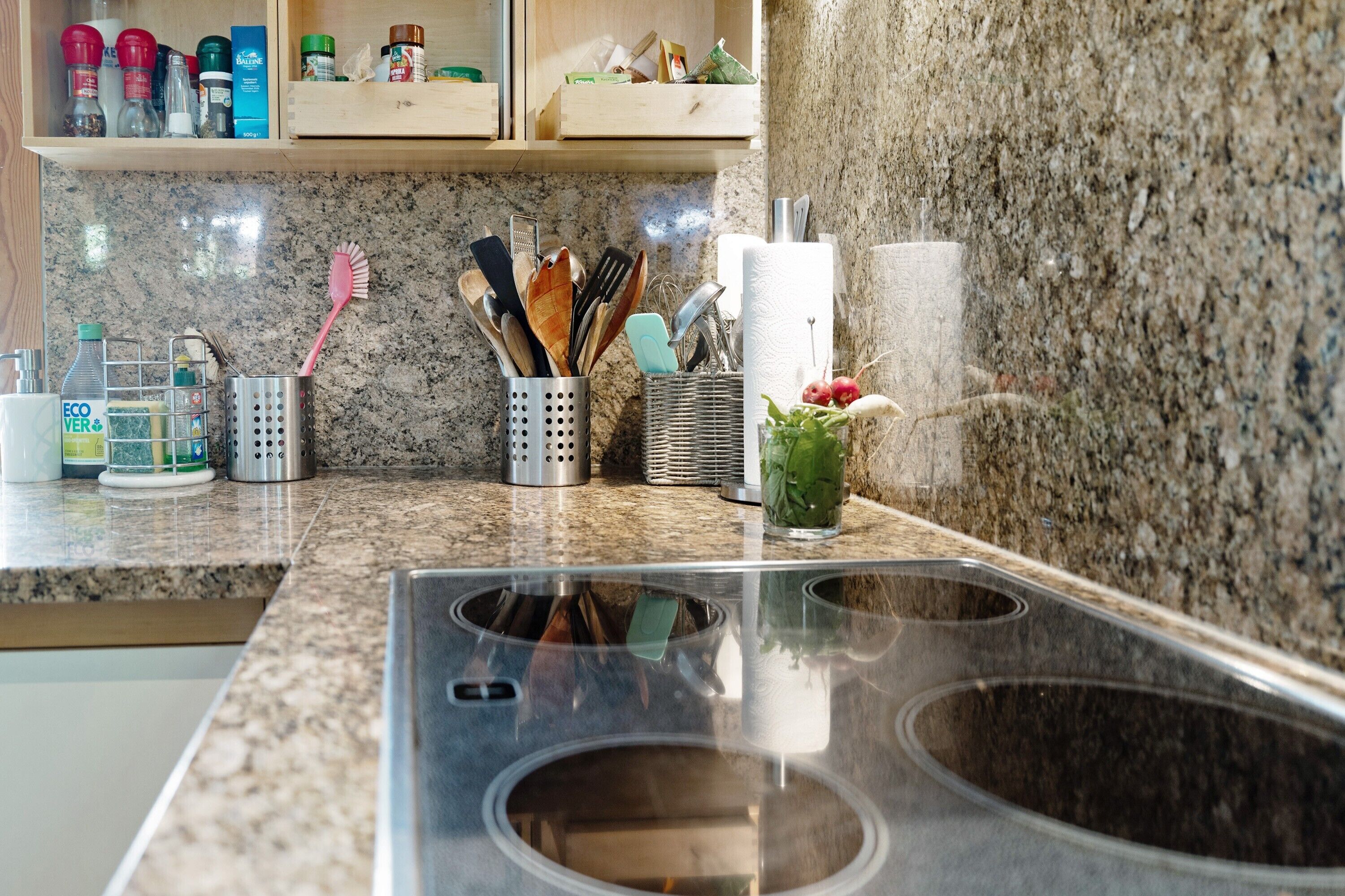 A kitchen with granite countertops, a stainless steel sink, and various kitchen utensils and appliances.
