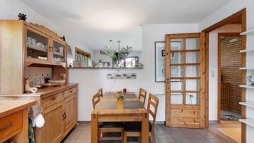 Een eethoek met een houten tafel, stoelen en een kast met glazen deuren.
