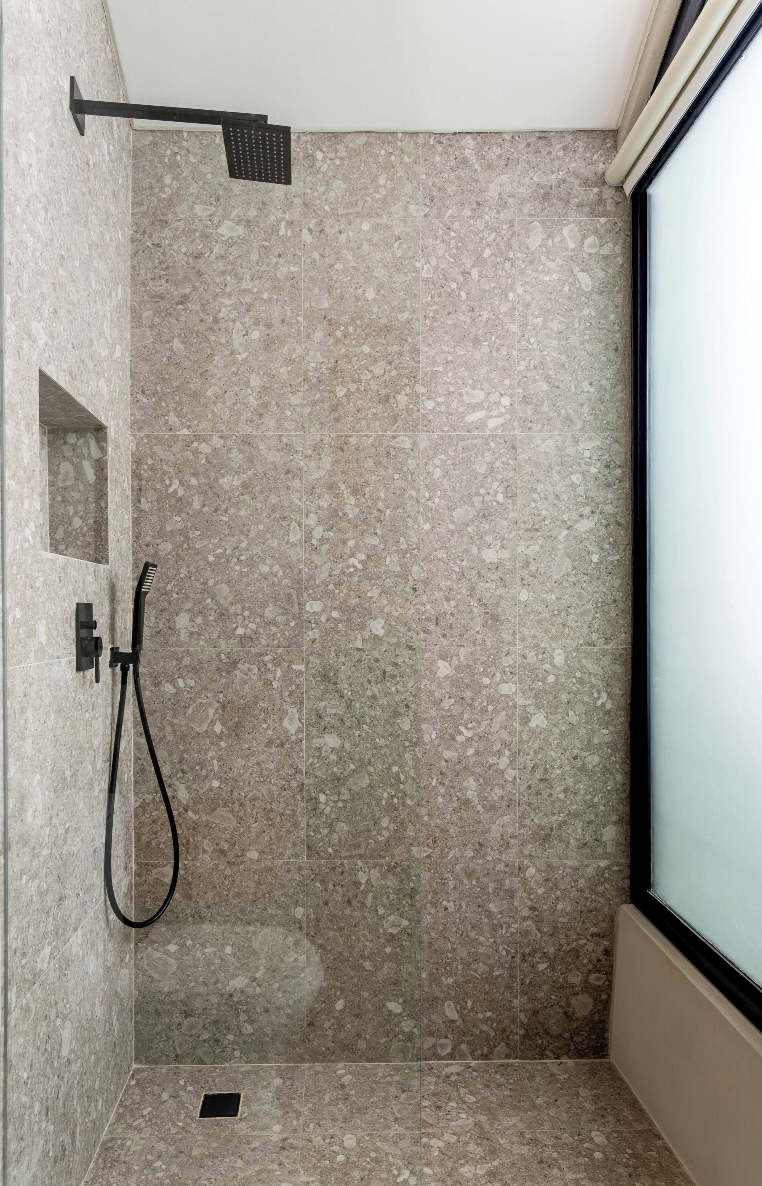 A small, enclosed shower area with a handheld showerhead and a wall-mounted faucet.