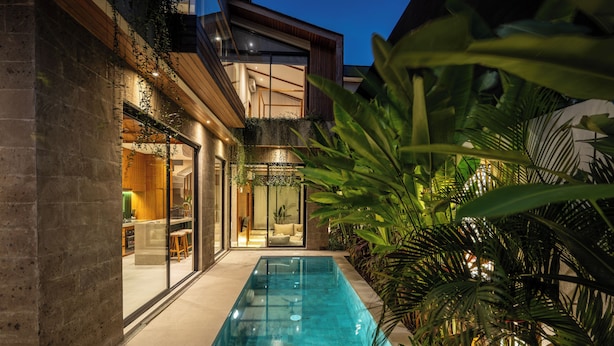 A modern house with a swimming pool, a glass door entrance, and a balcony with plants. - Nanna Villa Unit 1 by Betterplace (Canggu)
