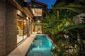 A modern house with a swimming pool, a glass door entrance, and a balcony with plants. - Nanna Villa Unit 1 by Betterplace (Canggu)