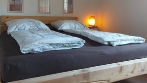 Ein Bett mit zwei Kissen und einer Nachttischlampe, ein hölzernes Kopfende und drei gerahmte Bilder an der Wand.