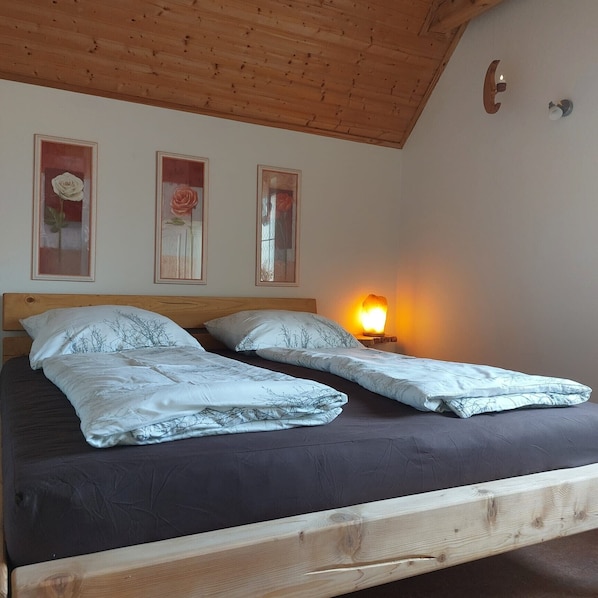 Un lit avec deux oreillers et une lampe de chevet, une tête de lit en bois et trois tableaux encadrés accrochés au mur.